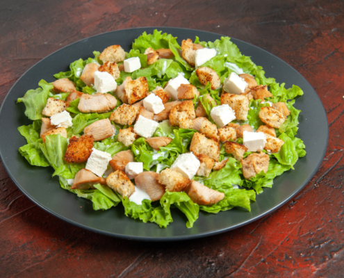 bottom-view-caesar-salad-oval-plate-dark-red-table